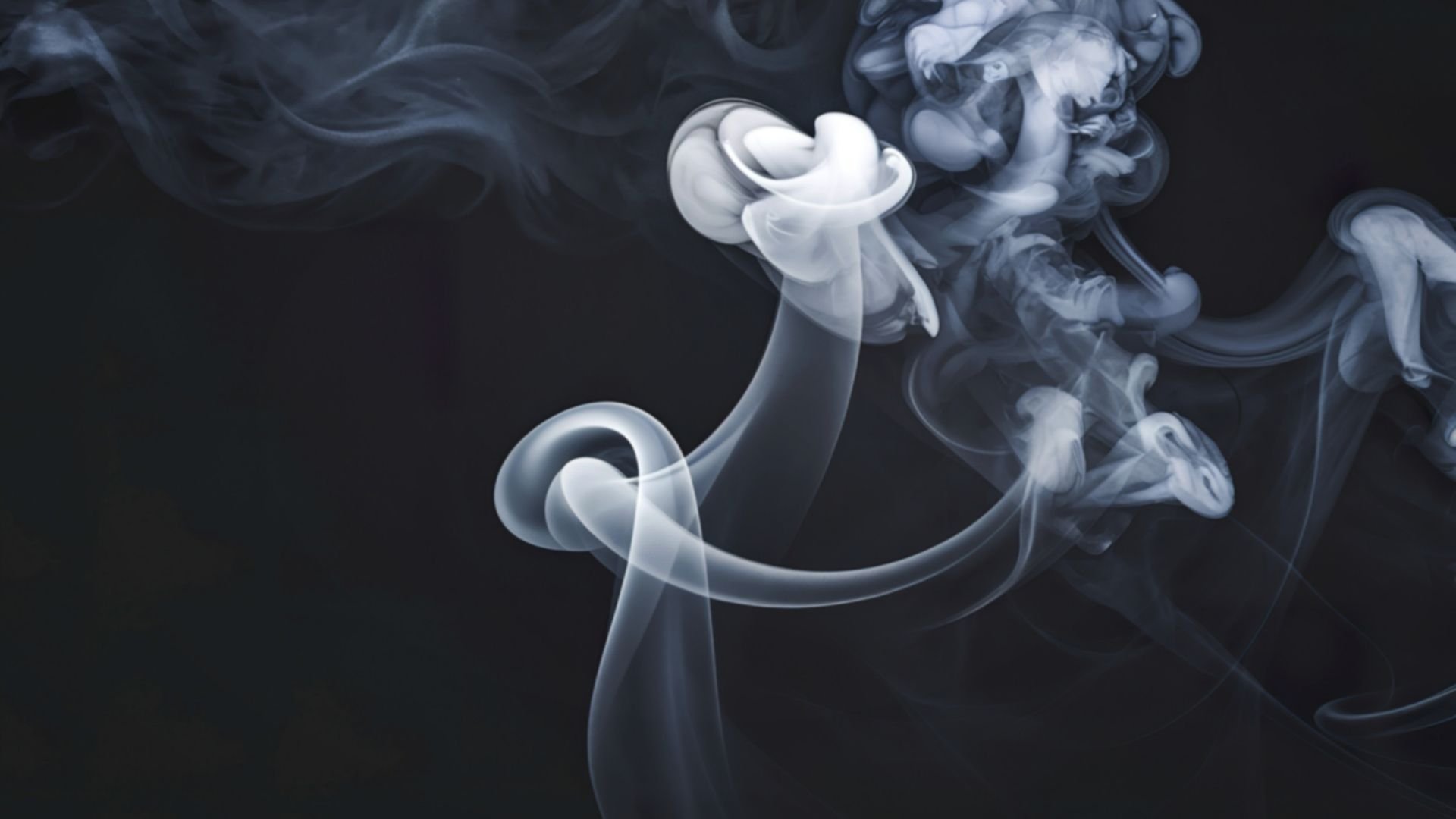 Wispy white and gray smoke swirling gracefully against a dark background