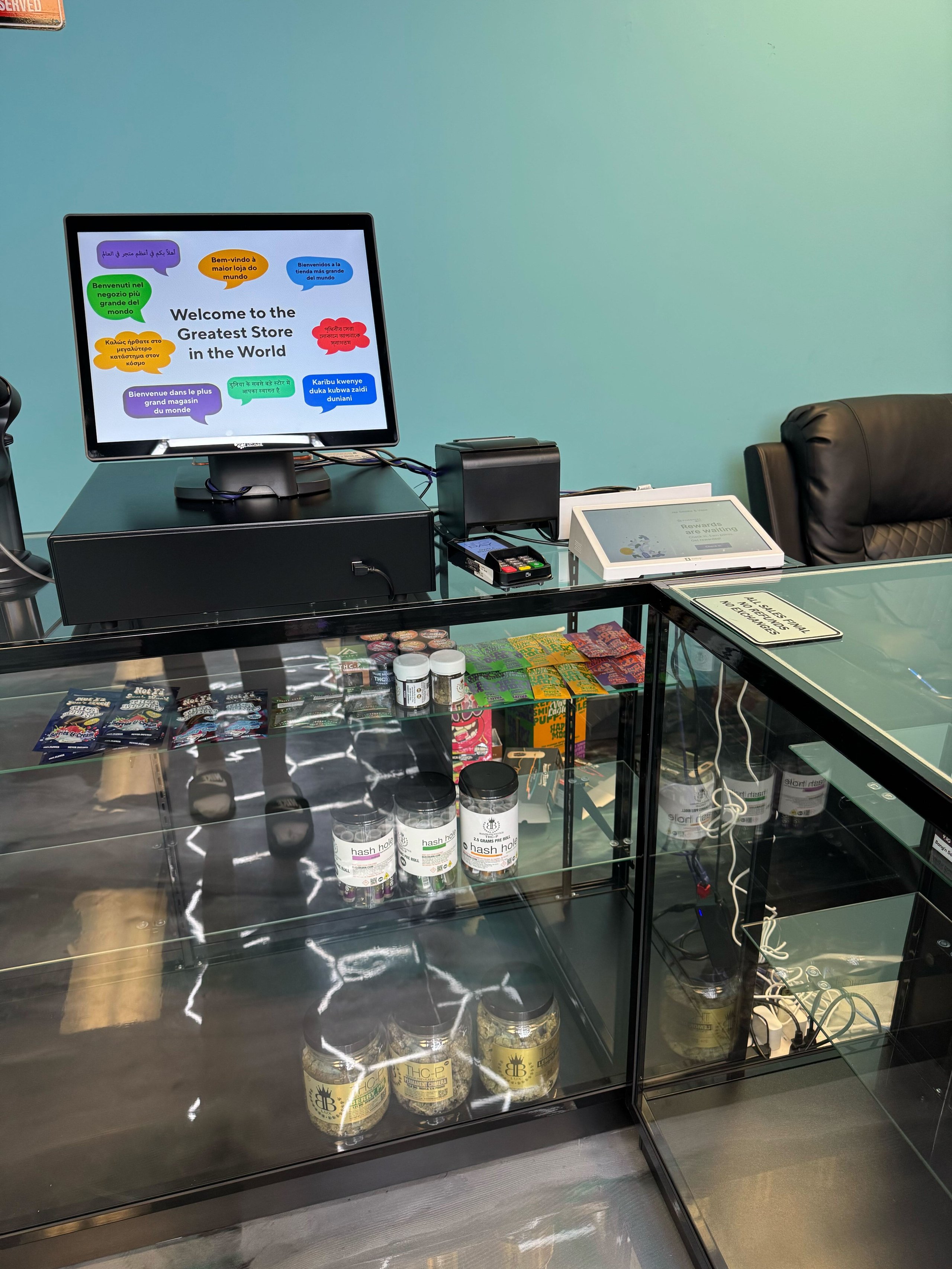Store counter with monitor displaying "Welcome to the Greatest Store in the World" in multiple languages