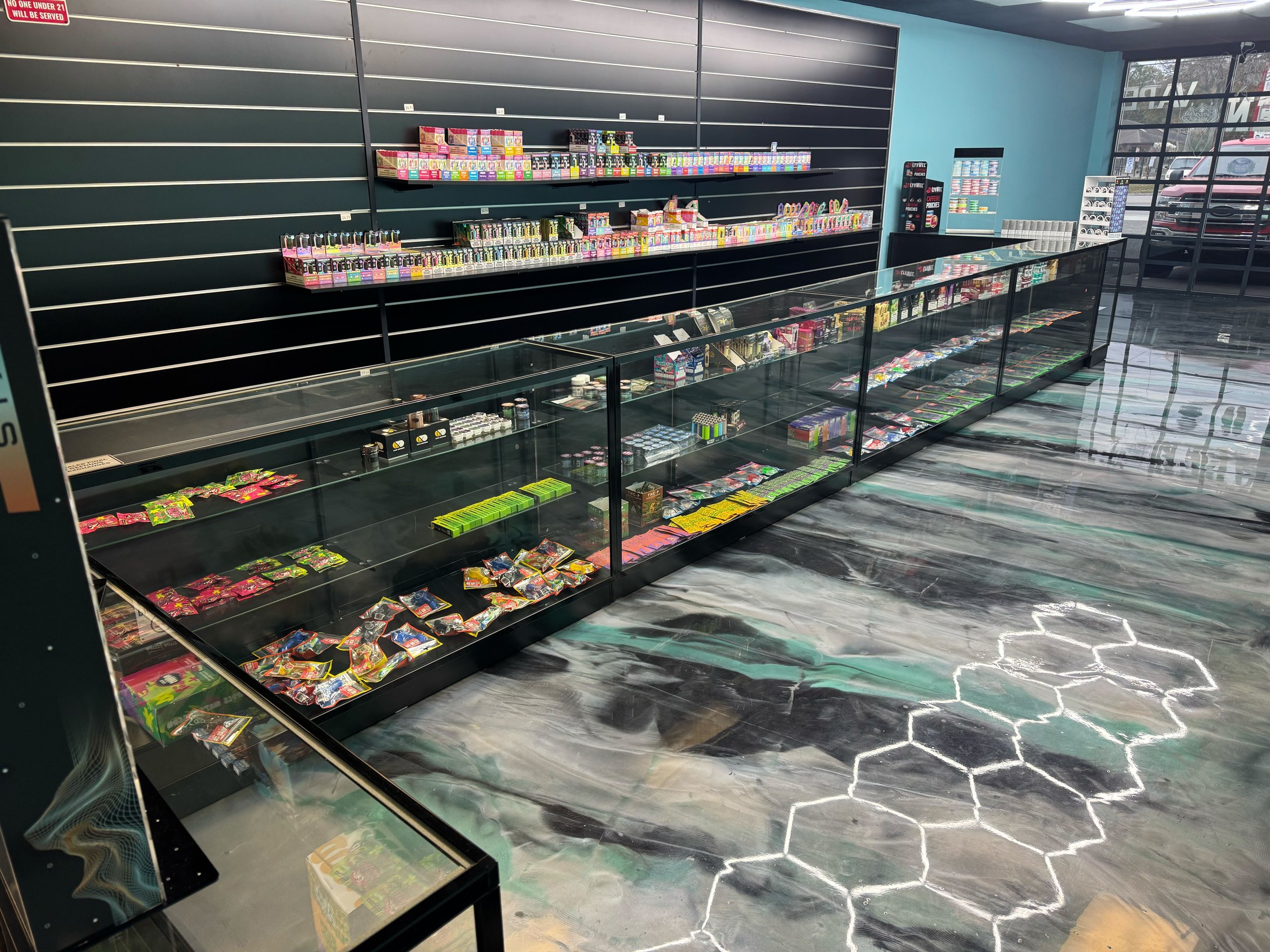 Convenience store display cases with colorful candy and snack products on shelves and in glass cases.