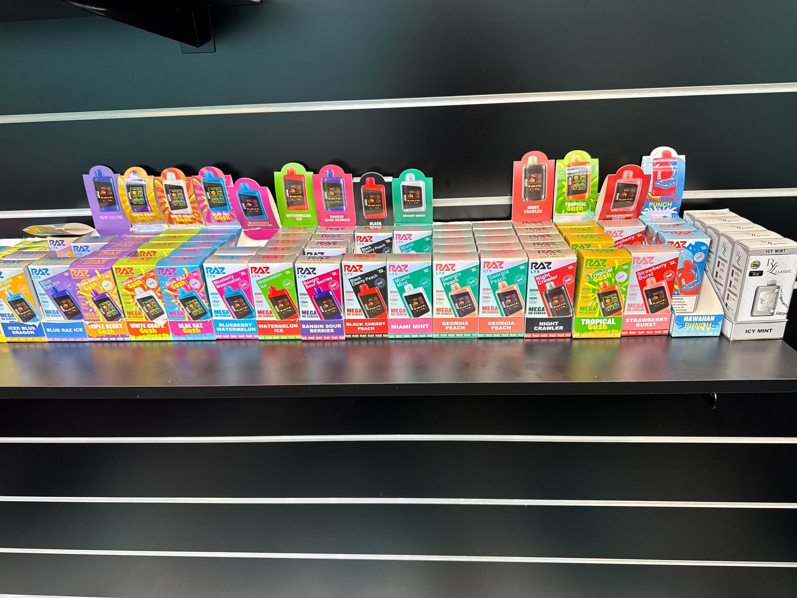 Colorful RAZ vape collection displayed on shelf with various flavor options and colored packaging.