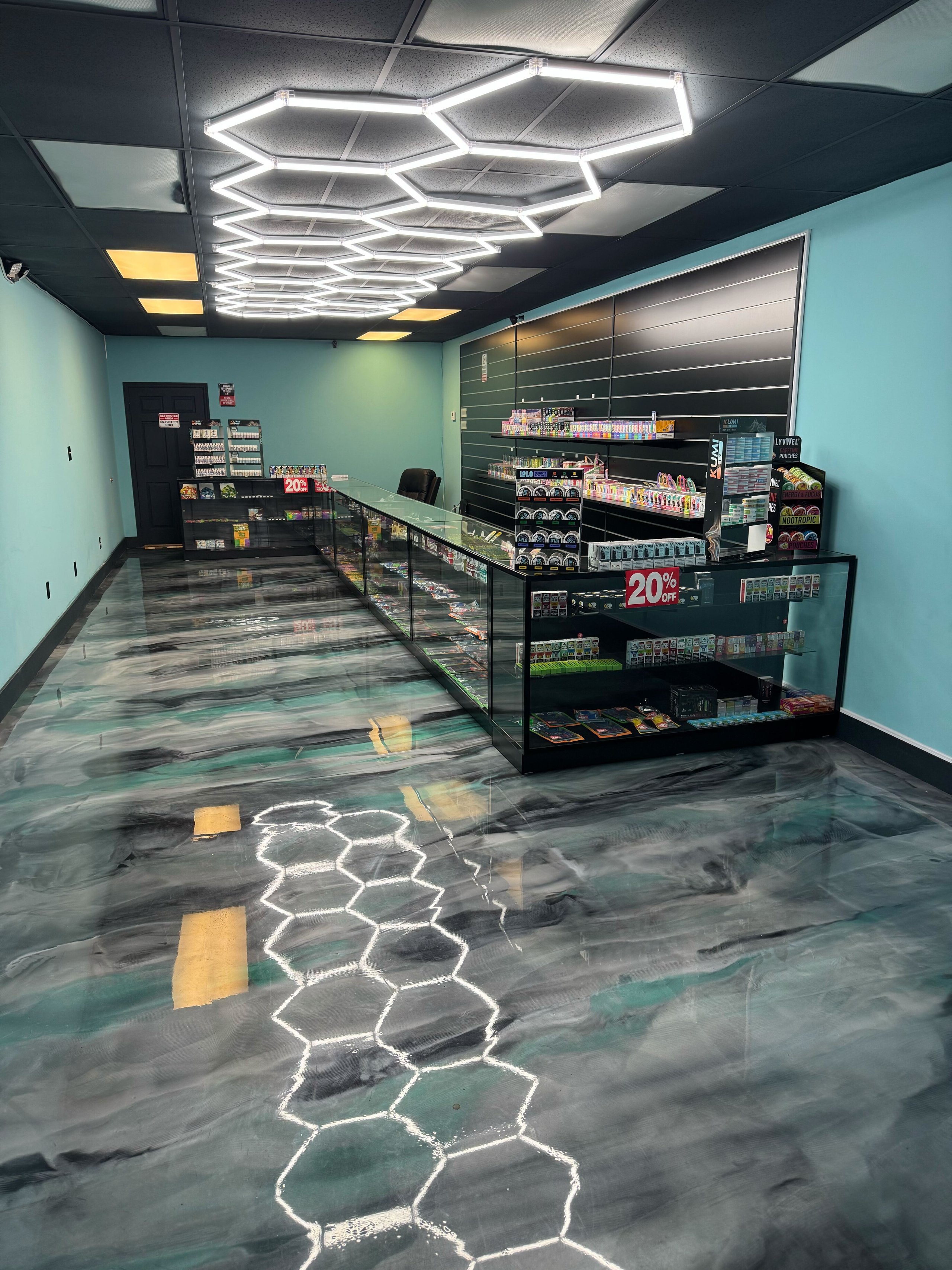 Modern convenience store interior with turquoise walls, hexagonal neon ceiling lights, and stocked shelves.