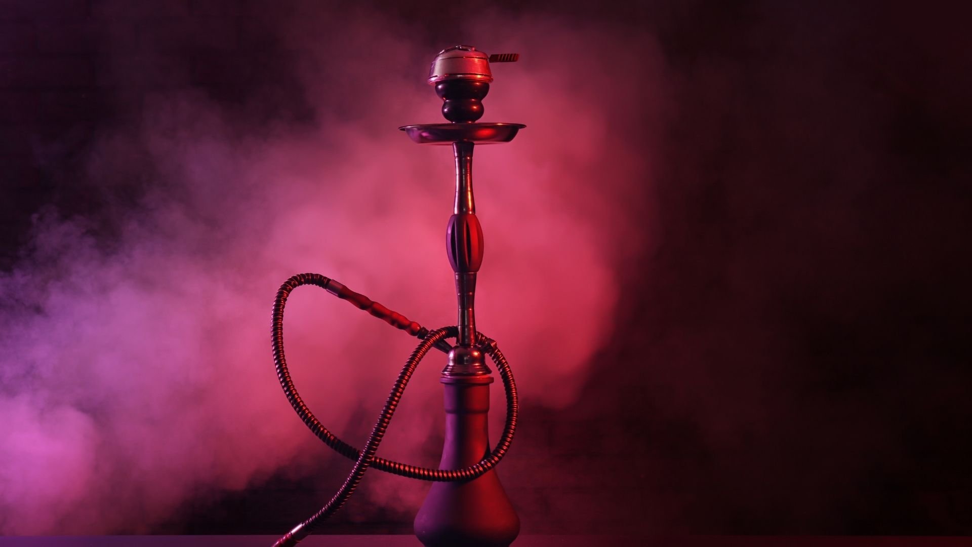 Ornate hookah pipe with glowing red bowl, hose, and atmospheric smoke background