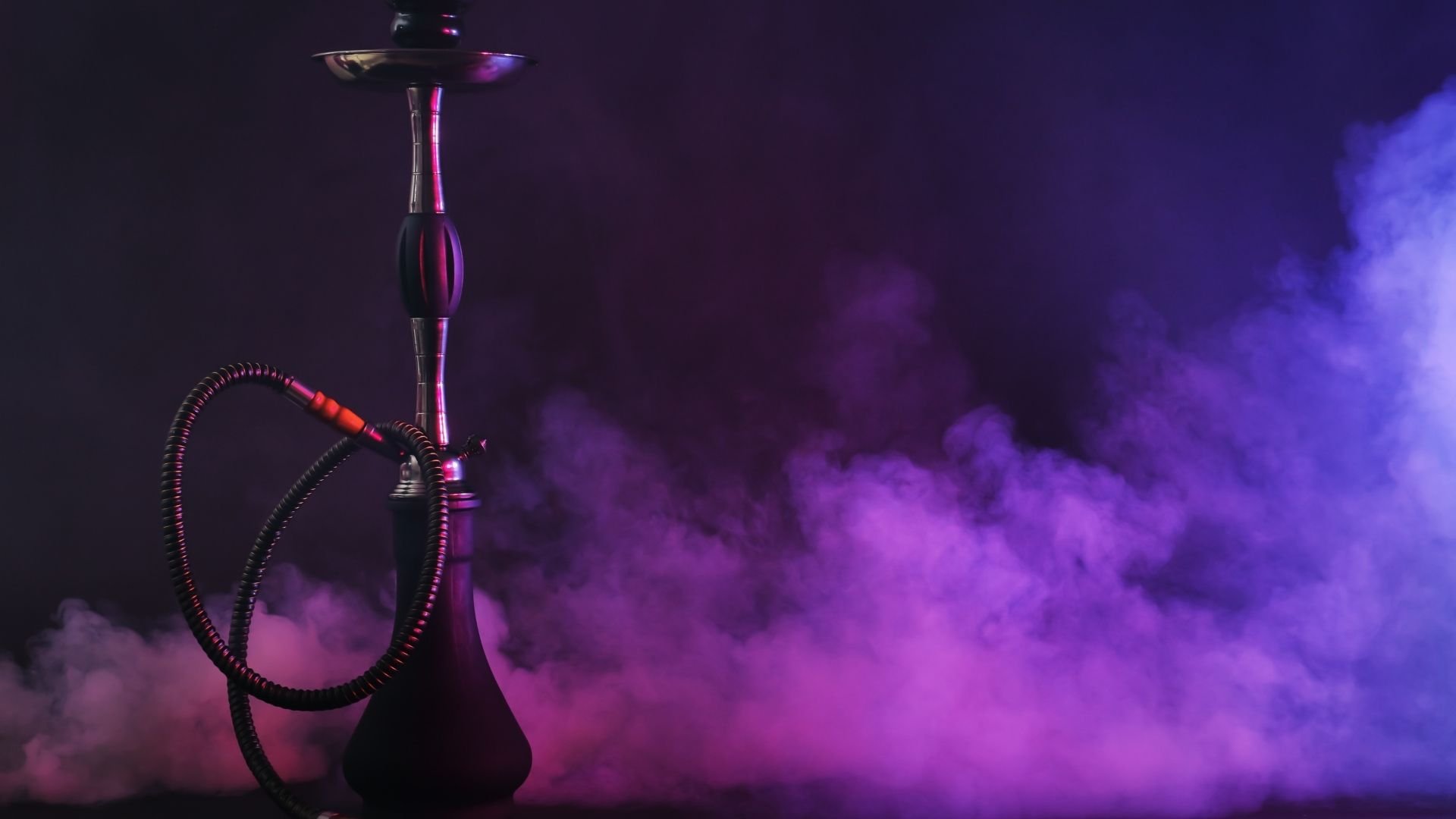 Ornate hookah with neon purple and pink lighting and thick smoke against dark background